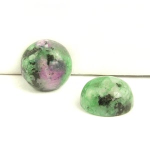 May include: Two green, black, and pink gemstone cabochons, each measuring 8 mm in diameter.