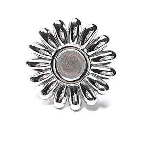 Peut inclure: Un objet argenté en forme de marguerite avec un élément central circulaire gris. L'objet a un diamètre de 8 mm, comme indiqué par le texte en bas. Les pétales de la marguerite sont détaillés et incurvés.