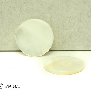 Könnte beinhalten: Zwei weiße runde Perlmuttknöpfe mit einem Durchmesser von jeweils 18 mm. Die Knöpfe sind glatt und haben einen leichten irisierenden Glanz.