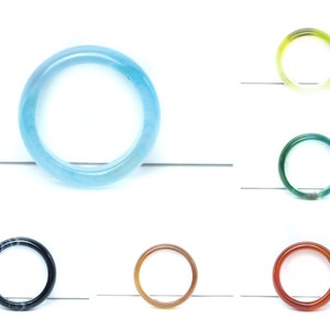 Könnte beinhalten: Sortiment an bunten Agat-Armreifen. Die Armbänder sind aus natürlichem Agatstein gefertigt und in verschiedenen Farben erhältlich, darunter Blau, Grün, Gelb, Rot und Schwarz.