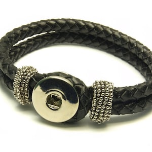 Könnte beinhalten: Ein schwarzes Lederarmband mit geflochtenem Design und silbernem Druckknopfverschluss.