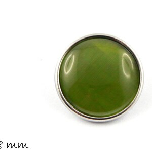 Può includere: Un bottone verde con un bordo in metallo argentato. Il bottone ha un diametro di 18 mm.