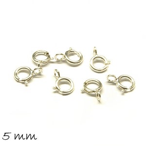 Könnte beinhalten: Sieben silberfarbene Metall-Hummerverschlüsse, jeweils 7 mm x 5 mm groß. Die Verschlüsse sind für die Schmuckherstellung gedacht und werden vor einem weißen Hintergrund gezeigt.