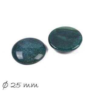 Può includere: Due cabochon rotondi in agata verde, ciascuno con un diametro di 25 mm. I cabochon hanno un aspetto screziato, marmoreo con una superficie liscia e lucida.