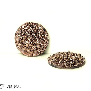 Könnte beinhalten: Zwei runde, 25 mm große, roségoldene Glitzer-Cabochons. Die Cabochons haben eine raue, strukturierte Oberfläche.