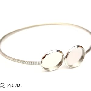 Può includere: Bracciale rigido in argento con due montature rotonde da 12 mm. Il bracciale è realizzato in filo ritorto.