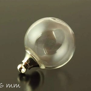 Op de afbeelding: Een heldere glazen bol met een zilverkleurige metalen basis en een kleine lus. De diameter van de bol is 16 mm. De achtergrond is donker en neutraal.