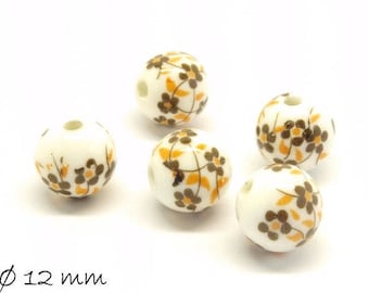 Puede incluir: Cinco cuentas de cerámica blanca con un patrón floral en marrón y naranja. Las cuentas tienen un diámetro de 12 mm.