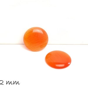 Könnte beinhalten: Zwei orangefarbene runde Cabochons mit einem Durchmesser von jeweils 12 mm. Die Cabochons haben eine glatte, glänzende Oberfläche und ein subtiles, gestreiftes Muster.