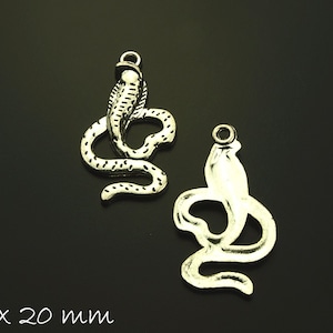 Può includere: Due ciondoli a forma di serpente in argento, uno avvolto e l'altro con la testa alzata, che misurano 34 x 20 mm.