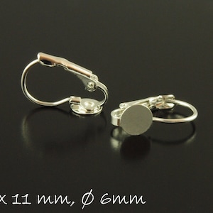 Może przedstawiać: Srebrne zapięcia do kolczyków z okrągłą podkładką o średnicy 6 mm do mocowania kaboszonu lub innych ozdób. Zapięcia mają wymiary 16 mm x 11 mm.