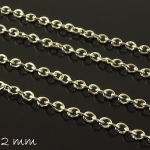 Könnte beinhalten: Silberkette mit einem 3 x 2 mm großen ovalen Glied. Die Kette ist in mehreren Strängen vor einem schwarzen Hintergrund abgebildet.