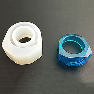 Peut inclure: Une bague en résine bleue transparente avec un design facetté, présentée à côté d'un moule en silicone pour la fabrication de la bague.