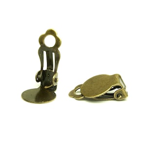 May include: Two antique gold-toned metal earring clips. The clips are designed to hold earrings in place. The clips are made of metal and have a smooth finish.