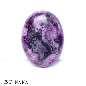 Peut inclure: Pierre précieuse ovale polie. La pierre présente un mélange de teintes violettes, noires et grises, avec un motif marbré. Dimensions : 40 x 30 mm.
