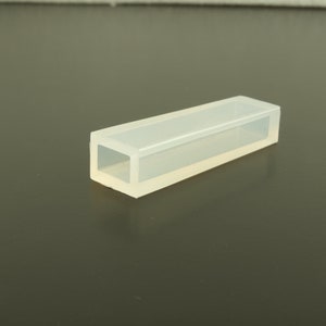 Könnte beinhalten: Eine transparente, rechteckige Silikonform mit einer quadratischen Öffnung. Die Form ist zum Erstellen von Kunsthandwerk aus Harz gedacht.