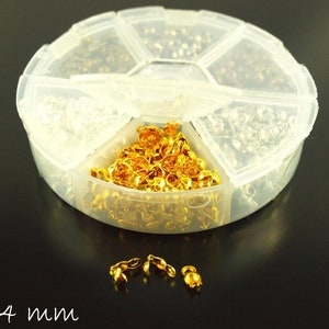 Könnte beinhalten: Ein klarer Kunststoff-Organizer gefüllt mit verschiedenen kleinen Schmuckteilen. Die Fächer enthalten goldfarbene und silberfarbene Metallkomponenten. Der Text "8 x 4 mm" ist in weißer Schrift unten links geschrieben.