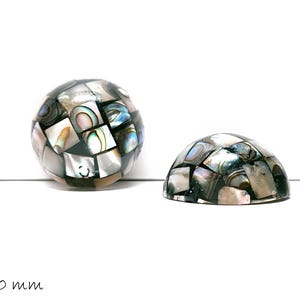 Könnte beinhalten: Zwei dekorative Mosaik-Abalone-Muschelteile. Eines ist eine Kugel, das andere eine Halbkugel. Die Abalone-Muschelteile bestehen aus kleinen, irisierenden, quadratischen Fliesen in Grau-, Schwarz- und Blautönen. Die Kugel hat einen Durchmesser von ca. 20 mm.