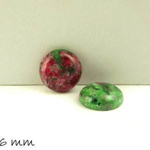 Könnte beinhalten: Zwei runde Cabochons mit einem Durchmesser von 16 mm. Einer ist grün mit weißen und schwarzen Wirbeln. Der andere ist rosa mit weißen und grünen Wirbeln.