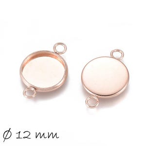 Könnte beinhalten: Zwei runde, roségoldfarbene Fassungen für die Schmuckherstellung. Jede Fassung hat eine flache Basis und eine Schlaufe zum Befestigen. Der Durchmesser beträgt 12 mm. Ideal für Anhänger.