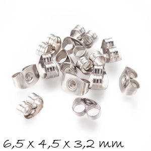 Könnte beinhalten: Nahaufnahme einer Reihe silberner Ohrringverschlüsse. Die Verschlüsse sind aus Metall und haben ein Doppelzinken-Design. Die Verschlüsse sind 6,5 x 4,5 x 3,2 mm groß.