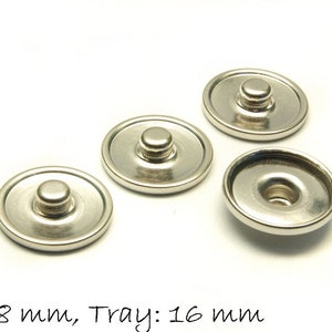Puede incluir: Cuatro botones a presión plateados, cada uno con un diámetro de 18 mm y un tamaño de bandeja de 16 mm. Los botones tienen un centro elevado con un pequeño agujero en el medio.