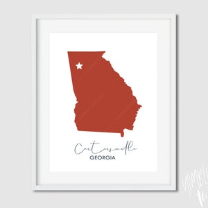May include: A printable art print featuring a red outline of the state of Georgia with a white star in the center. The text "Cartersville, GEORGIA" is printed below the state outline.