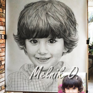 May include: A black and white pencil drawing of a young boy with short brown hair. The drawing is on a large sheet of paper and is framed by a wooden easel. The boy is wearing a plaid shirt and has a friendly smile. The artist's signature, "Melnik O.", is written in cursive below the drawing.