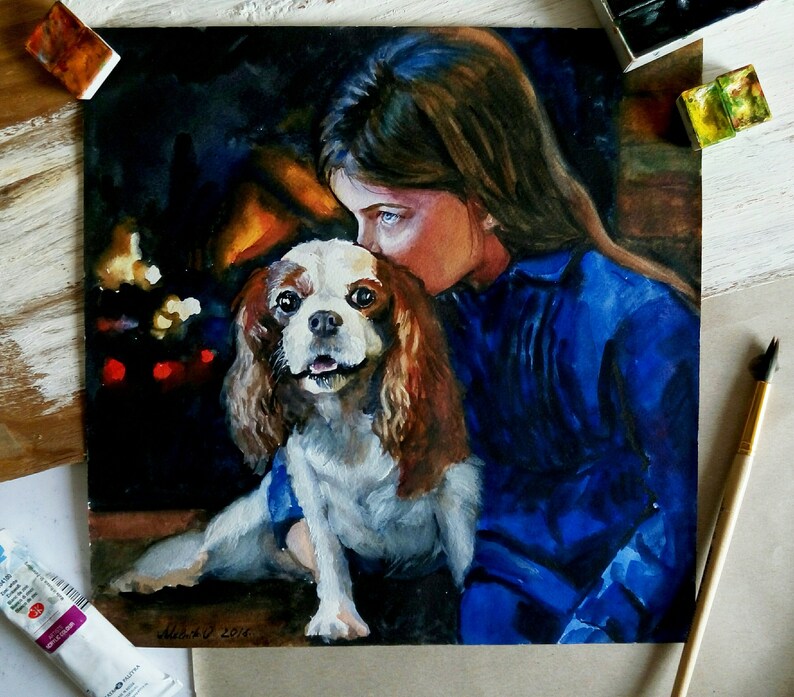 May include: A watercolor painting of a young girl with long brown hair, wearing a blue shirt, cuddling a white and brown Cavalier King Charles Spaniel dog. The painting has a warm, cozy feel and depicts a close bond between the girl and her pet.