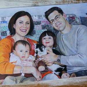Puede incluir: Un dibujo a l&aacute;piz de color de una familia con un gato. La familia est&aacute; sentada en una colcha de retazos colorida. La madre lleva un su&eacute;ter naranja y sostiene un beb&eacute;. El padre lleva un su&eacute;ter gris y sostiene un gato. La hija lleva un su&eacute;ter rojo y sostiene la cola del gato. El gato es blanco y negro.