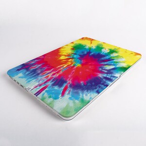 May include: A rectangular laptop hard shell case featuring a vibrant tie-dye pattern with radiating splashes of yellow, red, blue, purple, and green colors. The protective cover has a smooth finish and covers the top surface of the electronic device.
