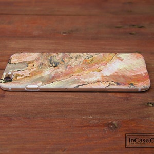 May include: A phone case with a colorful abstract design featuring shades of brown, orange, pink, and white. The design resembles a natural wood grain pattern.