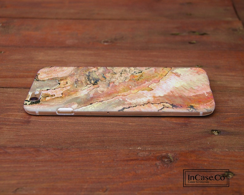 May include: A phone case with a colorful abstract design featuring shades of brown, orange, pink, and white. The design resembles a natural wood grain pattern.
