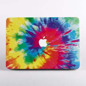 May include: A laptop skin featuring a vibrant tie-dye pattern with swirling colors of yellow, red, blue, and green. The design radiates from the center, where a white Apple logo is clearly visible against the colorful, abstract background.