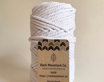 Może przedstawiać: Biały sznur bawełniany, nawinięty na szpulę, z przymocowaną brązową papierową etykietą. Etykieta zawiera tekst "Rock Mountain Co." i dane kontaktowe firmy.