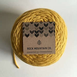 May include: A ball of yellow cotton rope with a brown label that reads "ROCK MOUNTAIN CO. rockmountain.co | @rockmountainco"
