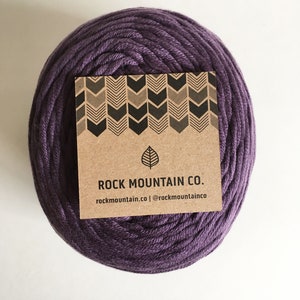 May include: A ball of deep purple cotton rope with a brown paper label that reads "ROCK MOUNTAIN CO. rockmountain.co | @rockmountainco"