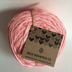 May include: A ball of pink cotton yarn with a brown paper tag that reads "ROCK MOUNTAIN CO. rockmountain.co | @rockmountainco"
