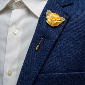 May include: A navy blue blazer with a yellow flower lapel pin.