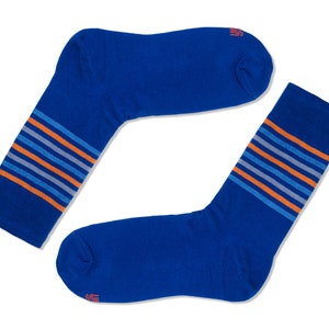 May include: A pair of blue socks with orange and gray stripes. The socks are folded in half and are lying on a white background.