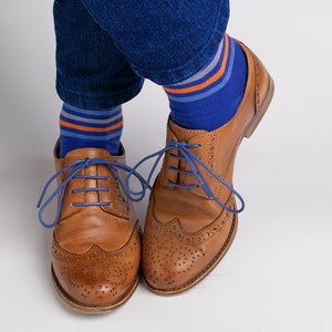 May include: Brown leather oxford shoes with blue shoelaces and blue and orange striped socks.