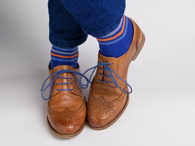 May include: Brown leather oxford shoes with blue shoelaces and blue and orange striped socks.