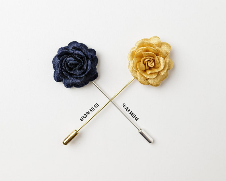 May include: Two fabric flower lapel pins with gold and silver needles. The flowers are navy blue and gold.