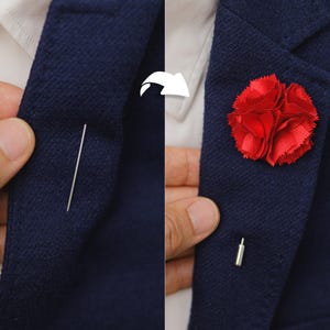 A close-up view of a person's lapel, showing a red flower pin and a needle used to attach it to the jacket.