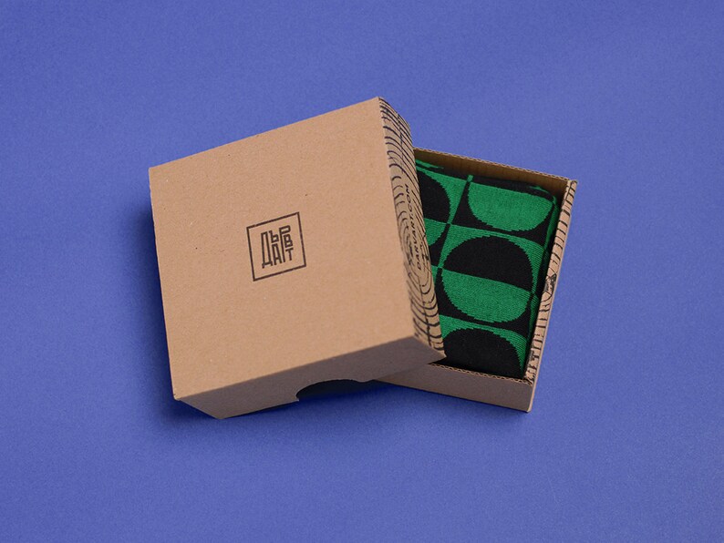 May include: A brown cardboard box with a black and green patterned fabric inside. The box has the word "DAIT" printed on it in black.