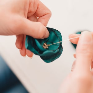 a woman is tying a green bow with a needle