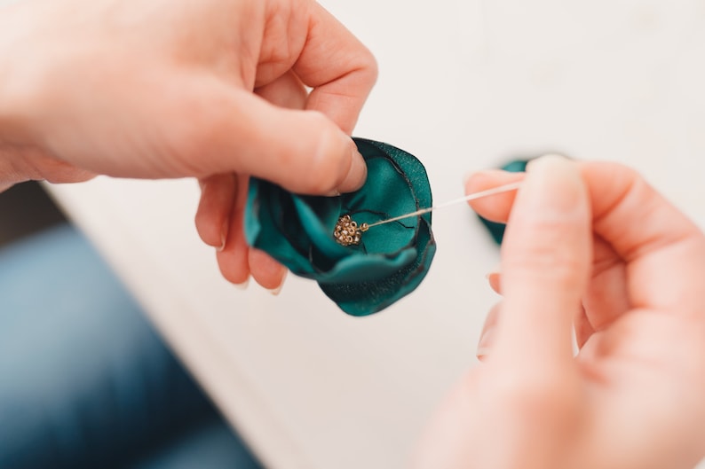 a woman is tying a green bow with a needle