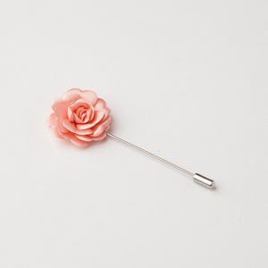A single pink rose flower pin is shown against a plain white background.