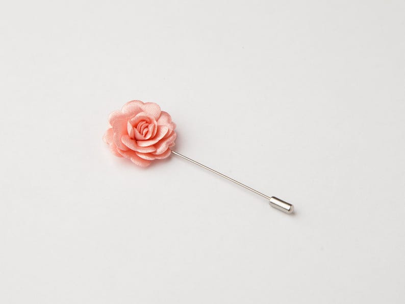 A single pink rose flower pin is shown against a plain white background.