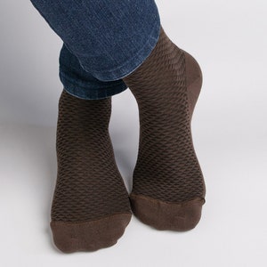 Peut inclure: Une paire de chaussettes marrons avec un motif texturé. Les chaussettes sont faites d'un matériau doux et confortable et sont parfaites pour un usage quotidien.